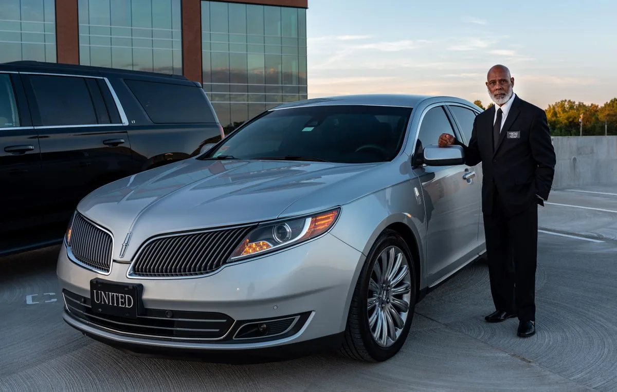 Professional chauffeur beside an executive car for corporate travel